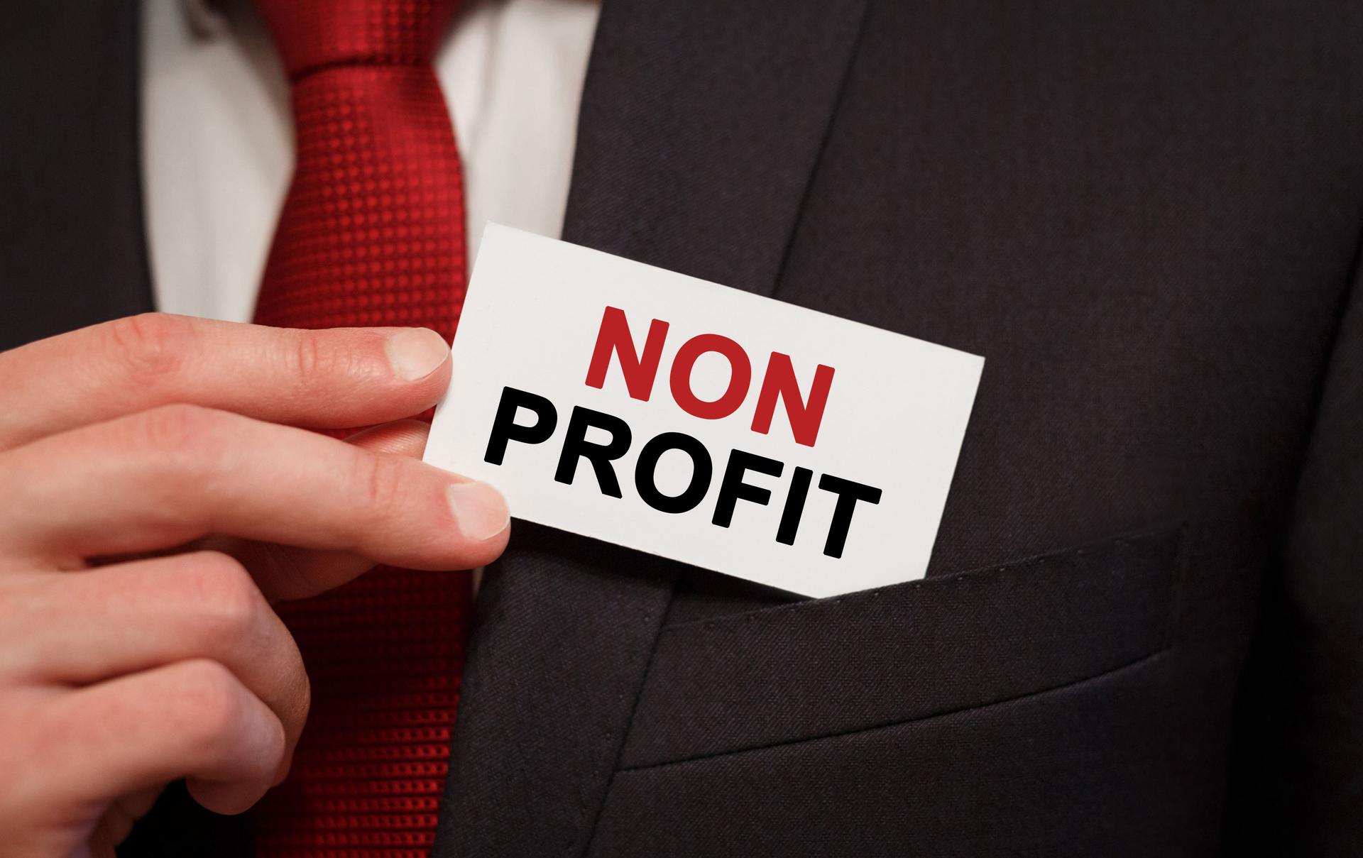 Businessman putting a card with text Non Profit in the pocket